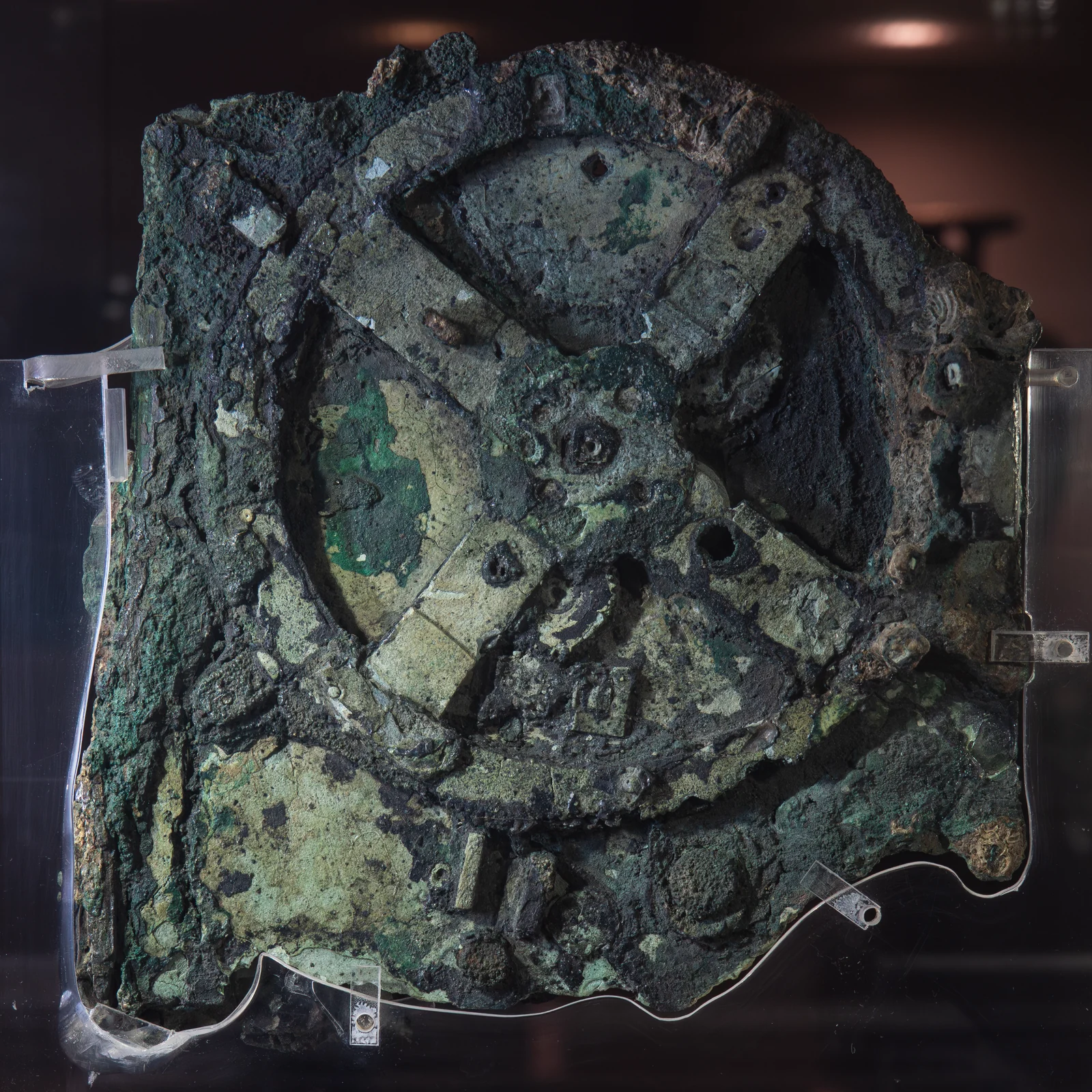 Fragment A of the Antikythera mechanism: corroded green bronze with the four-spoked great wheel at its centre